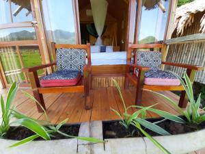 a porch with two chairs and a bed at Little Mai Chau Home Stay in Mai Châu