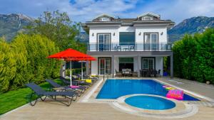 a house with a swimming pool with chairs and an umbrella at Blue - 4 Bedroom Holiday Villa in Hisarönü in Oludeniz