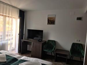 a room with a tv and a desk with two chairs at Hotel Margaritar in Buşteni