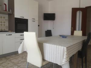 加里波利的住宿－Le meraviglie del Mare，厨房配有带白色椅子的桌子、桌子和桌子。