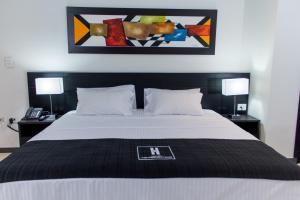 a bedroom with a bed with a painting above it at Hotel Metropolitano in Neiva