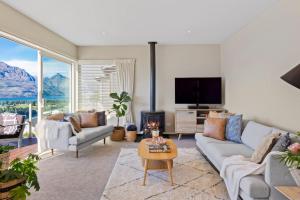 a living room with a couch and a tv at Unbeatable Panoramic Lake & Mountain & Garden Views in Queenstown