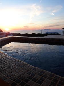 un charco de agua con la puesta de sol en el fondo en Kiklamino Sunset Studios en Oia