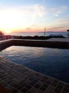 a pool of water with the sunset in the background at Kiklamino Sunset Studios in Oia