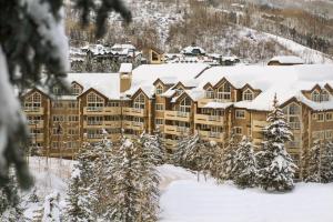 um grande edifício coberto de neve com árvores em St. James Place em Beaver Creek