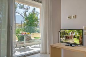 ein Wohnzimmer mit einem TV und einem Balkon in der Unterkunft Apollo Hotel 1 in Georgioupoli