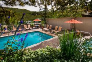 a pool with chairs and umbrellas in a yard at The Pines Lodge, a RockResort in Beaver Creek