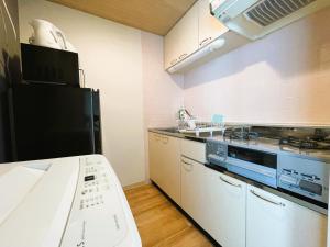 a kitchen with a black refrigerator and a stove at サービスアパ―トメントＳＡＰＰＲＯ札幌ステーション5 in Kita-rokujō