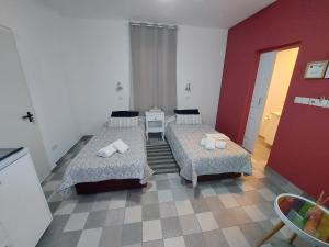 Habitación con 2 camas y pared roja. en Magdalene's City House Inn en Lárnaca