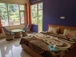 a bedroom with a bed and a table and windows at Golden View B&B in Dharamshala