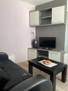 ein Wohnzimmer mit einem Tisch und einem TV in der Unterkunft Kopaonik apartmani u Kraljevim Čardacima , Čar 27 i 6-13 in Kopaonik