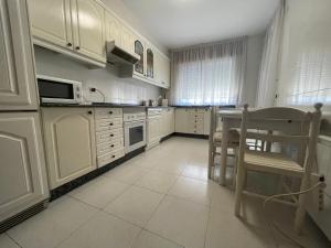cocina con armarios blancos, mesa y microondas en Oktheway Rua Nova 3D, en Sarria