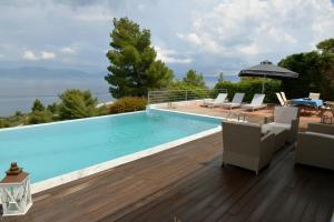 a swimming pool with chairs and an umbrella on a wooden deck at VILA AMALIA in Theologos
