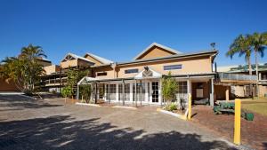 a large building with palm trees in front of it at Nightcap at Hinterland Hotel Nerang in Gold Coast