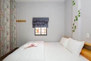 a bedroom with a white bed and a window at TUTI HOSTEL in Da Nang