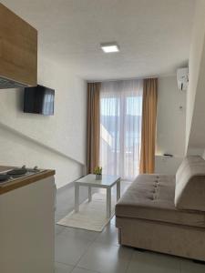 een woonkamer met een bank en een tafel voor een raam bij Apartments Villa Glavinić in Neum