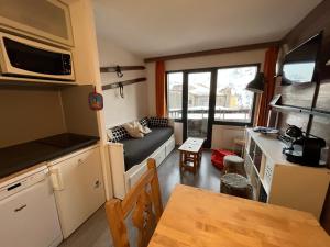 een kleine keuken en een woonkamer met een bank en een tafel bij Avoriaz appartement 4pers plein sud skis aux pieds in Morzine