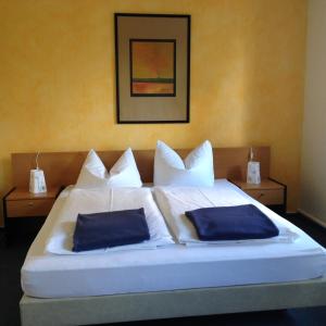 a bedroom with a bed with two blue pillows on it at Landhotel Lindenschänke in Dresden