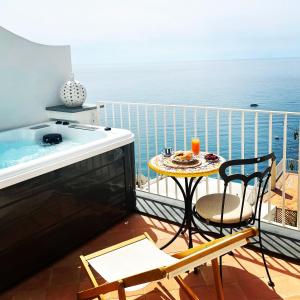 einen Balkon mit einem Whirlpool, einem Tisch und Stühlen in der Unterkunft Villa Fortuna in Positano