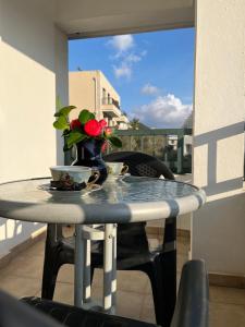 una mesa con un jarrón de flores en el balcón en Apartments and Room MV, en Petrovac na Moru