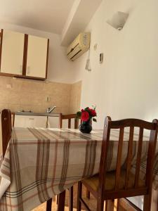 a kitchen with a table with a vase of flowers on it at Apartments and Room MV in Petrovac na Moru