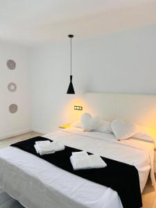 1 cama blanca grande con 2 toallas en Jacaranda Apartments & Studios, en Es Canar