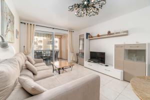 a living room with a white couch and a tv at Tropical Holiday Apartment in Los Cristianos