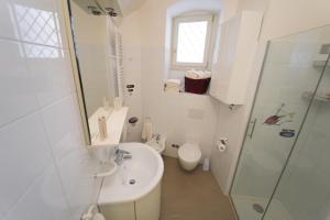 Baño blanco con lavabo y aseo en Santa Cesarea Residence Casa Vacanze, en Matera