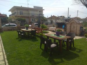 een tuin met tafels en stoelen op het gras bij Simos Apartments in Korinós