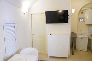 ein Bad mit einem WC und einen TV an der Wand in der Unterkunft Santa Cesarea Residence Casa Vacanze - La vetta del Sasso Barisano in Matera