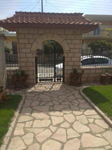 een bakstenen poort met een boog in een tuin bij Simos Apartments in Korinós