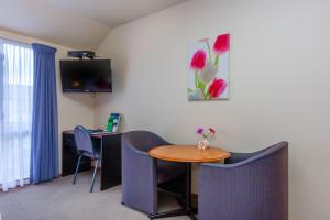 Habitación con mesa, sillas y TV. en Deans Bush Motel, en Christchurch