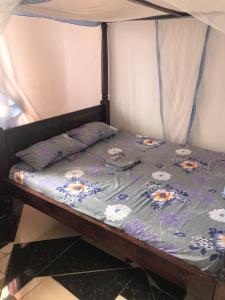 1 cama con edredón azul y almohadas en ANN AKAN NIDO’S en Malindi