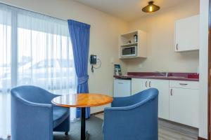a small kitchen with a table and blue chairs at Deans Bush Motel in Christchurch