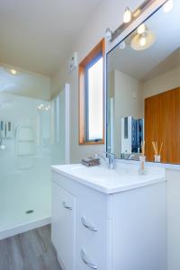 een witte badkamer met een wastafel en een spiegel bij Deans Bush Motel in Christchurch