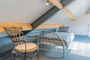 1 dormitorio con 1 cama y 1 silla en el ático en B&B de Bommelhoeve, en Wadenoijen