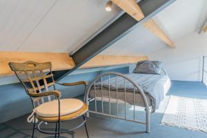 a bedroom with a bed and a chair in a attic at B&B de Bommelhoeve in Wadenoijen