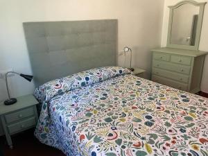 a bedroom with a bed with a colorful comforter and a mirror at La Fuentona in Celorio