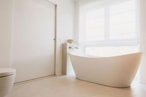 a white bathroom with a tub and a window at STEILLAGE - Design Moselsuiten mit Panoramablick und SPA in Brauneberg