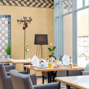 バート・ザルツフレンにあるHotel Arminiusのテーブルと椅子と窓のあるダイニングルーム