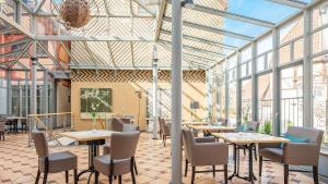 a restaurant with tables and chairs and glass ceilings at Hotel Arminius in Bad Salzuflen