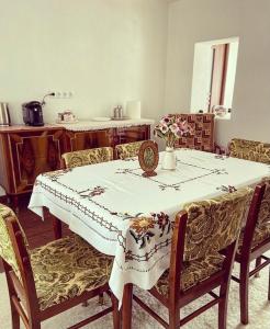 a dining room table with a white table cloth and chairs at Country House Hățăgel in Hăţăgel