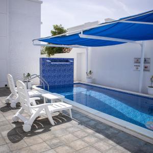 a pool with two chairs and a blue umbrella at THE POOL VILLA - TANUF in Nizwa