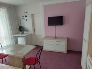 Habitación con mesa y TV en una pared rosa. en Azalka Penzion, en Brno