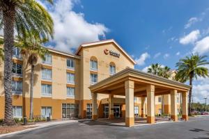 a hotel with palm trees in front of a building at Comfort Inn & Suites Orlando North in Sanford