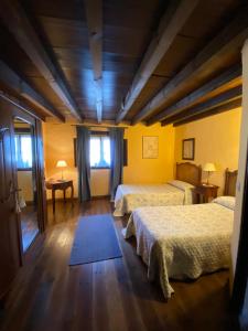 two beds in a room with yellow walls and wooden floors at Casa Rural Dos Reales in San Cristóbal de Boedo