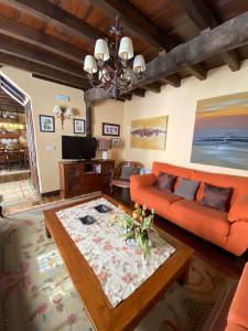 ein Wohnzimmer mit einem orangenen Sofa und einem Tisch in der Unterkunft Casa Rural Dos Reales in San Cristóbal de Boedo
