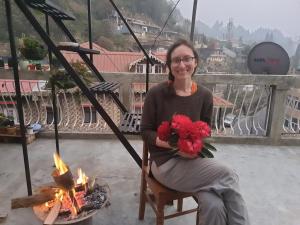 a woman sitting in a chair holding a bouquet of flowers at Langdak Homestay in Darjeeling