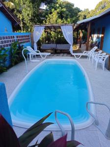 a swimming pool with chairs and a table and a swimming pool at pousada corais de abrolhos in Caravelas