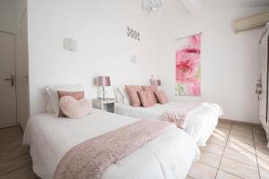 two beds in a room with white walls and pink pillows at Hôtel Le Méditerranée in Hyères